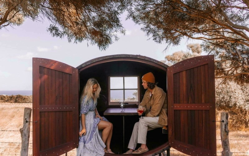 a couple sitting in the wine barrel tasting pod
