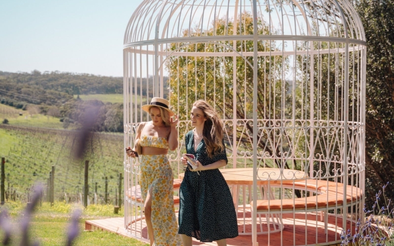 a South Australian vineyard with huge white cage seating area. Two beautiful girls walking past.